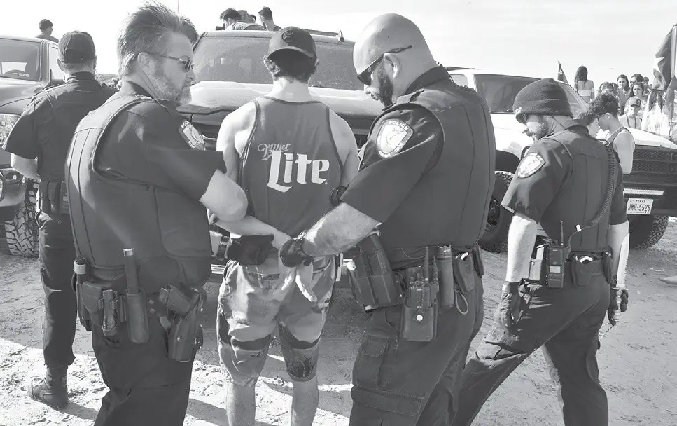 Port Aransas police handcuff a person suspected of underage drinking on the beach on Wednesday, March 14, during Spring Break. Officers also confiscated a knife from him. Staff photo by Zach Perkins