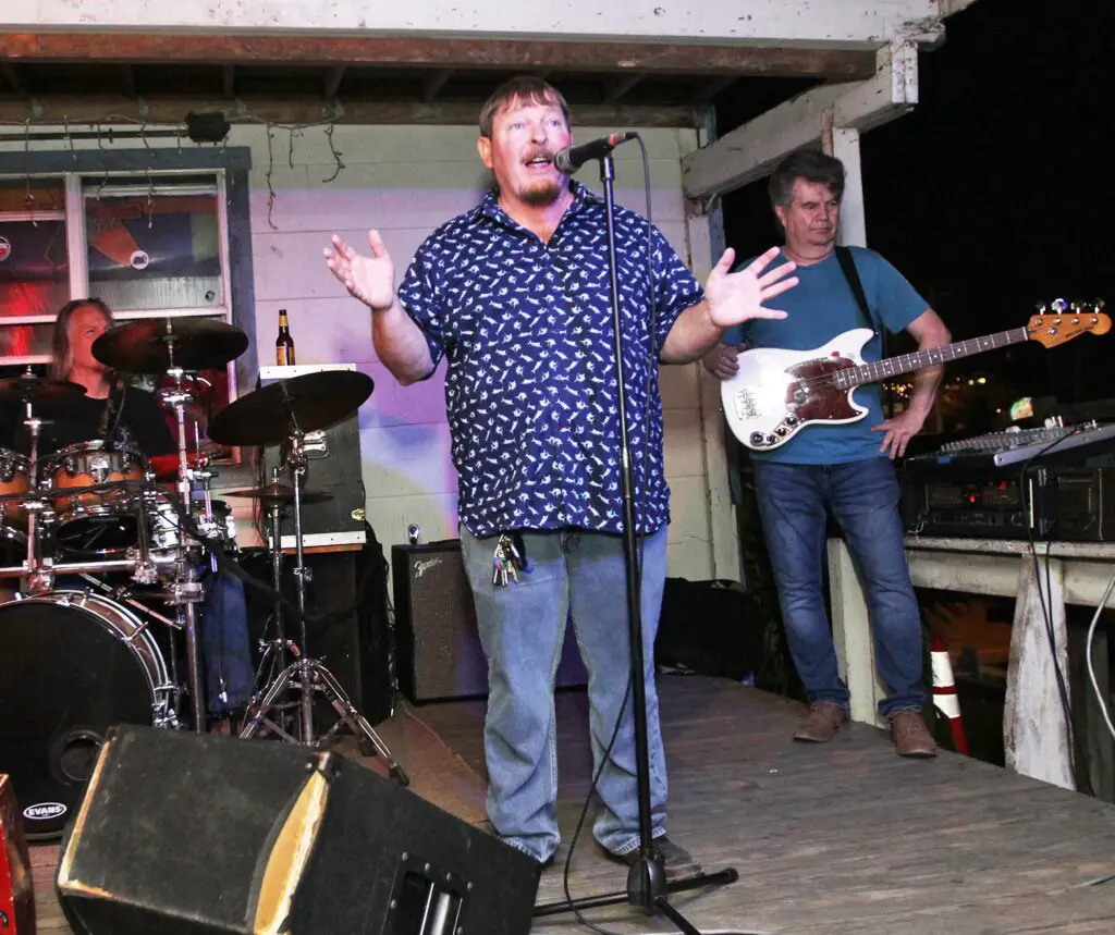 Standing on the bandstand at Shorty’s Place on the evening of Saturday, April 9, owner Edwin Myers announces that he intends to move the bar from its current location at 823 Tarpon St. to a lot at the intersection of Alister and Beach streets. Staff photo by Dan Parker