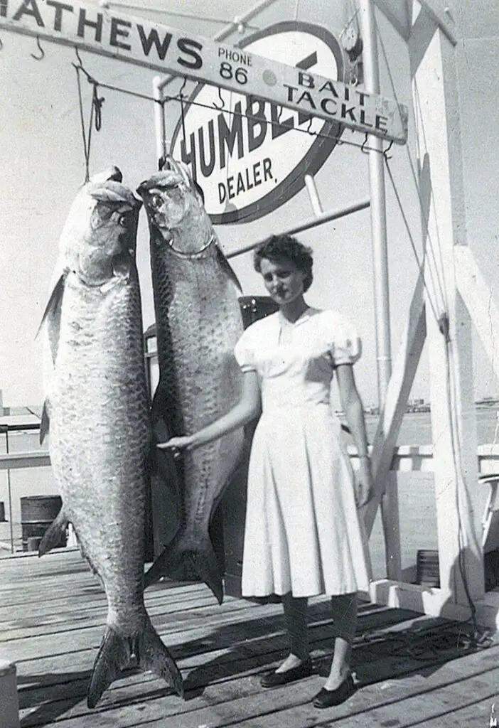 She stands with two big tarpon on a dock in Port Aransas. The photo is believed to have been shot around 1950.